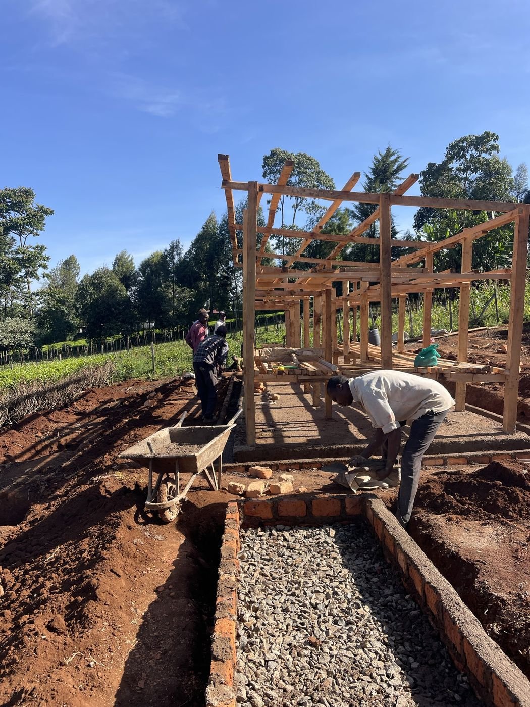 Builders laying the brick and concrete base of the apiary beside its timber frame